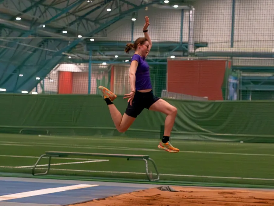 Aamu Hulmi hyppäämässä pituutta urheiluhallissa.